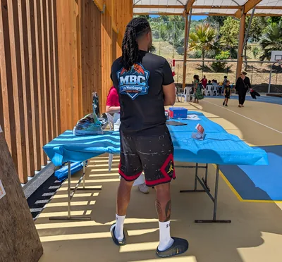 Un bénévole du MBC, en t-shirt du club, tient la table d'accueil lors d'un événement sur le terrain couvert de La Montagne.