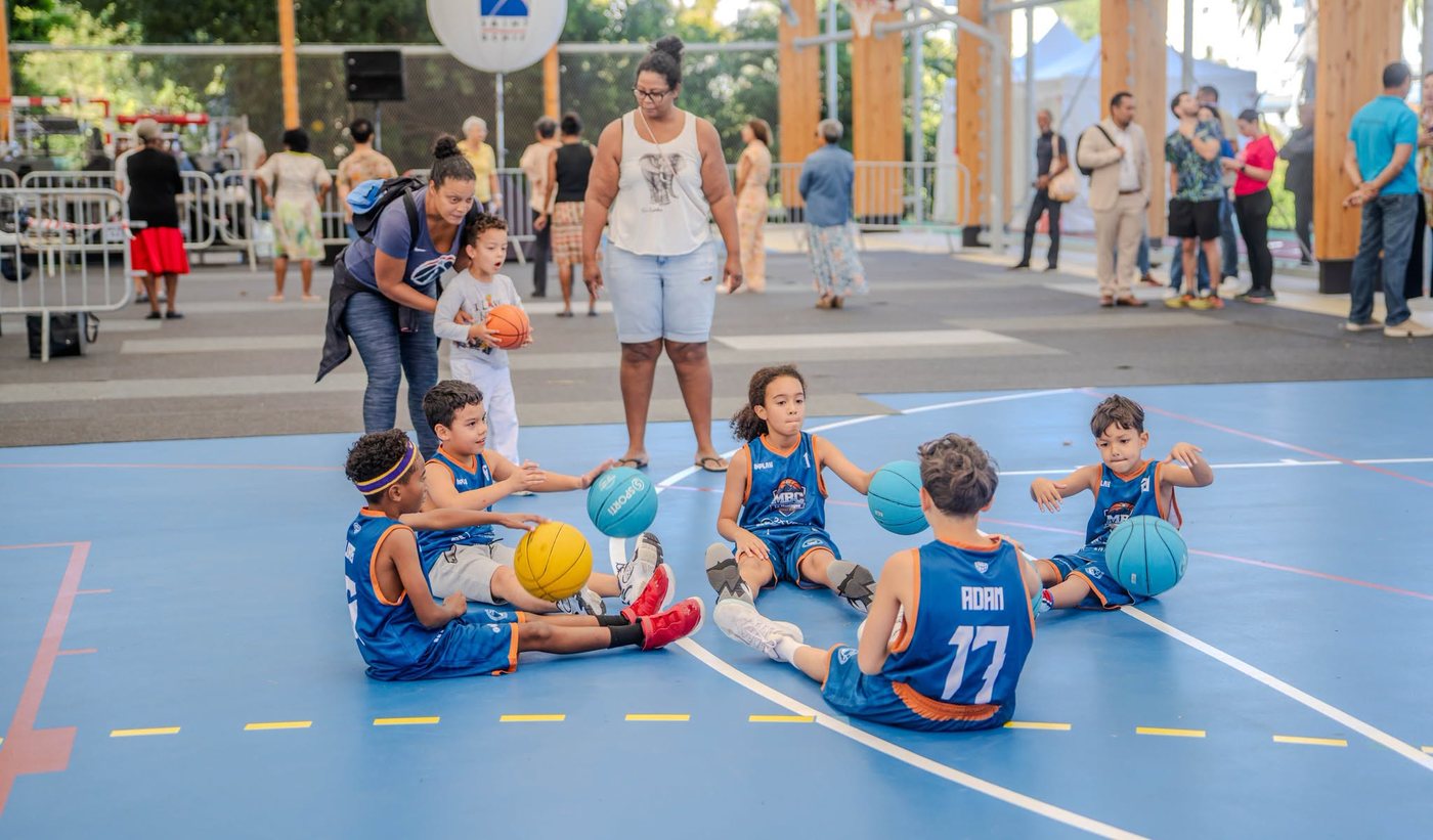 Enfants du MBC en maillot, assis en cercle avec leurs ballons lors d'une activité basket à La Montagne, Saint-Denis.