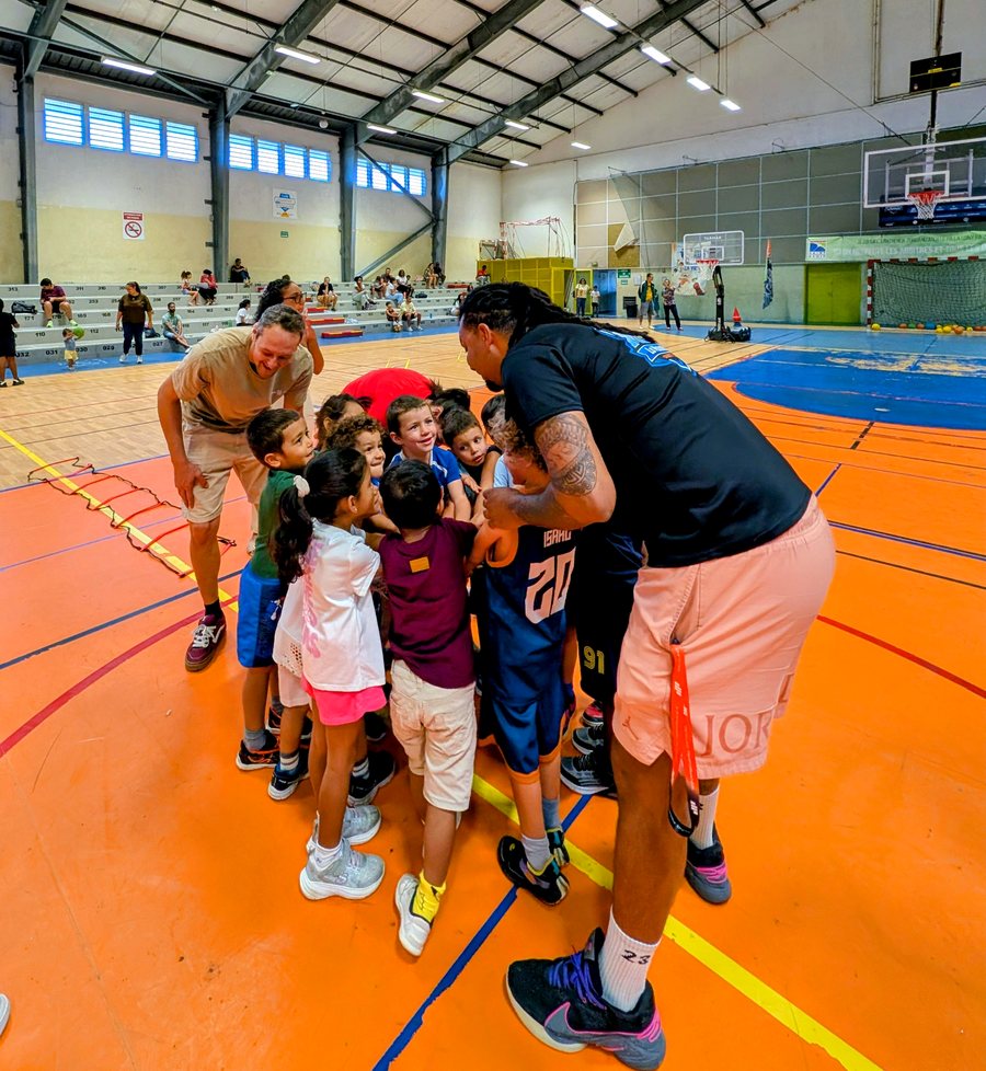 Deux encadrants du MBC La Montagne réunissent les enfants de l'école de basket en cercle au bord du terrain, au gymnase de Saint-Denis.